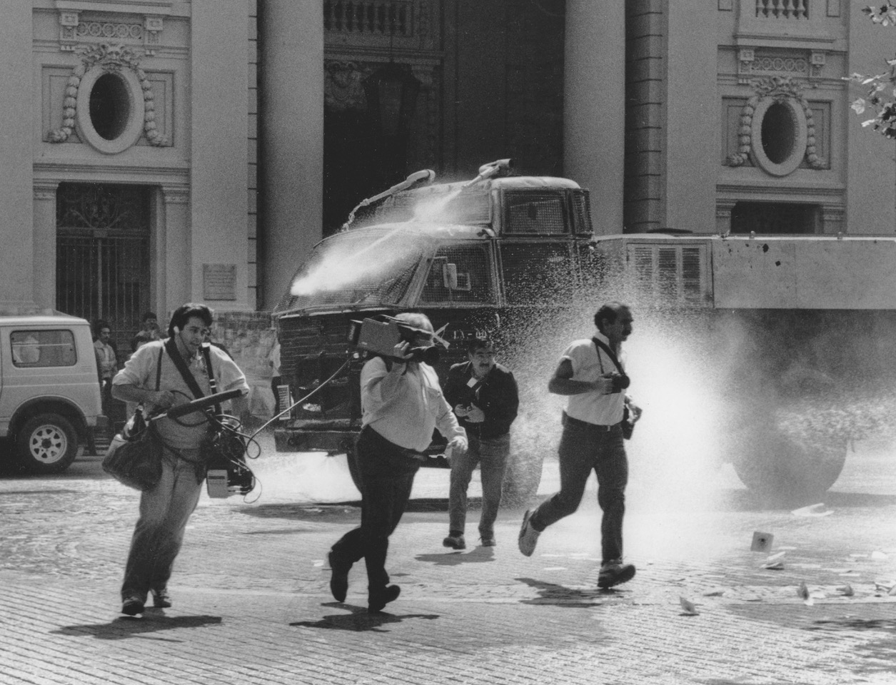 Journalists being chased by a water cannon