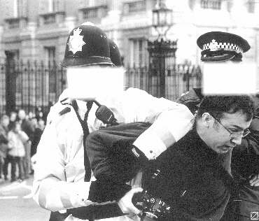 A photographer apparently being grappled by three police; we've masked their faces