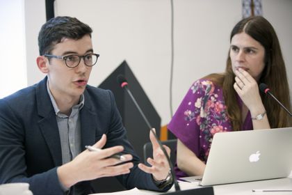 Jack Lehart (left, speaking) as Ann Gripper (left, with laptop)