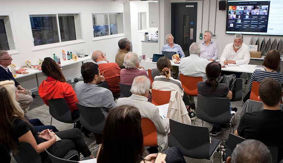 Photo taken at the October Branch meeting showing the panel speakers and a number of those attending in person plus a computer display on the wall showing those attending via Zoom.